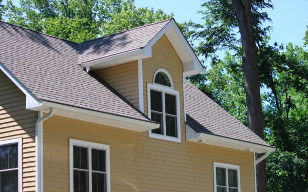 Tan colored home with white trim and gutters.